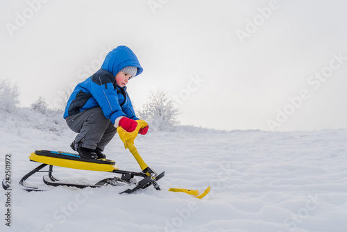 little child riding a snow scooter in winter