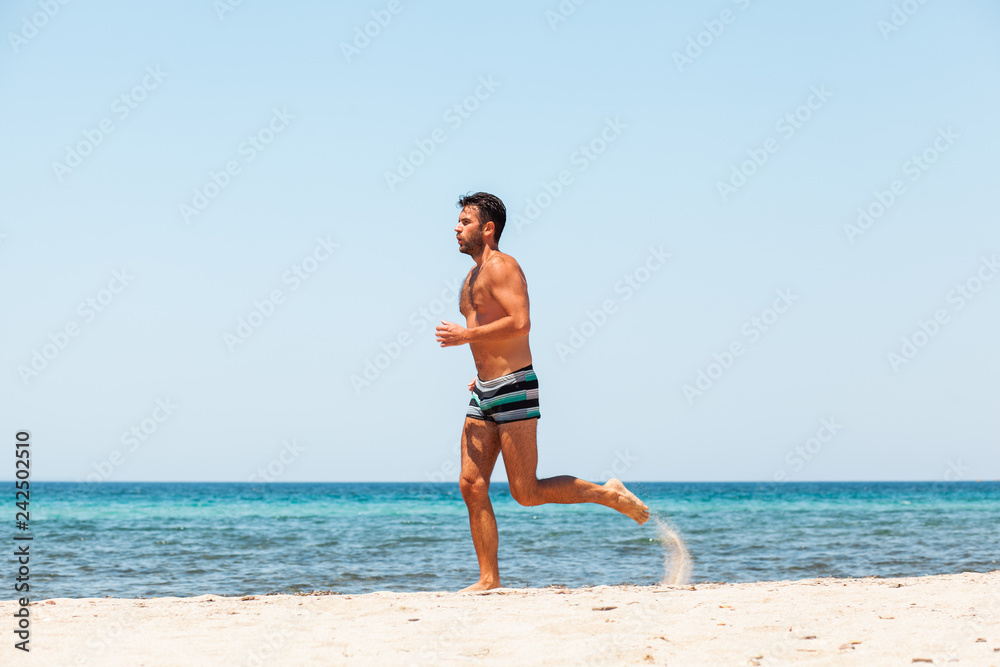 Young handsome man running on the beach