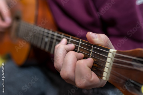 Young unidentifiable musician playing on the guitar shallow depth of field.