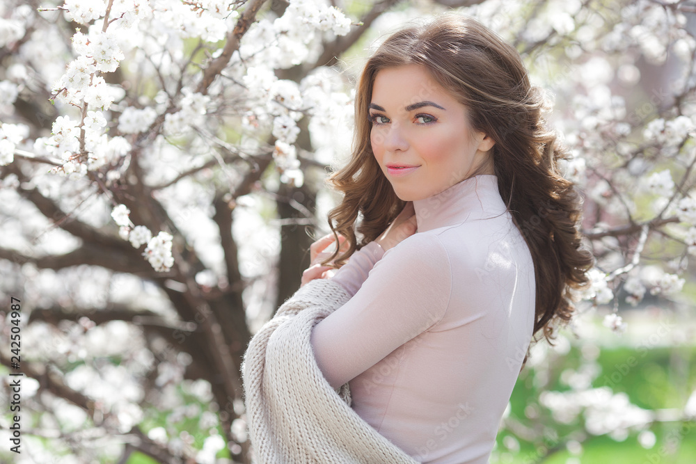 Young attractive woman on spring background with flowers. Close up portrait of beautiful girl make up. Lady outdoors in the garden