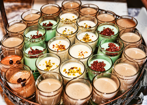 Numerous dessert glasses filled with coffee cream and panna cotta  filled with candied fruit and coffee beans