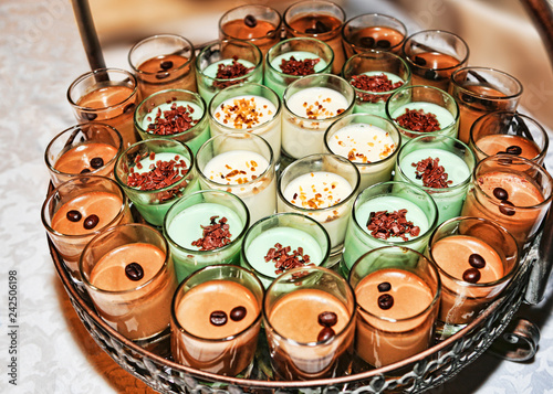 Numerous dessert glasses filled with coffee cream and panna cotta, filled with candied fruit and coffee beans