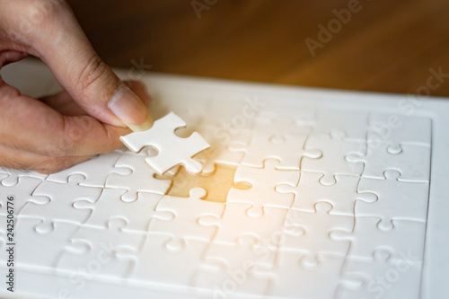 Hands of business people hold paper jigsaw puzzle and solving put pieces of the puzzle together. After Business group meeting to analyze and discuss the financial report,Investment Consultant solution