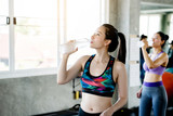 Portrait Asian women wearing exercise sportswear in the gym Hands holding a clean water bottle Drinking in the mouth to reduce the heat release that exercise and waste energy. Concept Health insurance