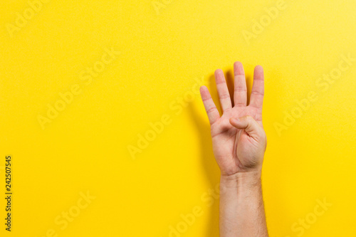 Man hand showing four fingers on yellow background. Number two symbol photo
