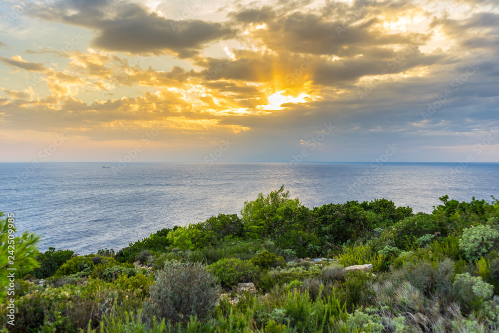 Greece, Zakynthos, Romantic orange sky as sun breaks through clouds at island coast