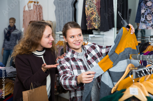 Women choosing cardigan in clothing shop