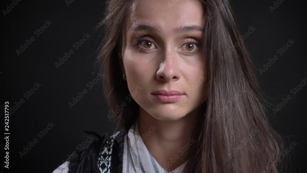 Close-up portrait of young caucasian long-haired woman watching calmly into camera on black background. Close-up portrait of young caucasian long-haired woman watching calmly into camera on black background.
