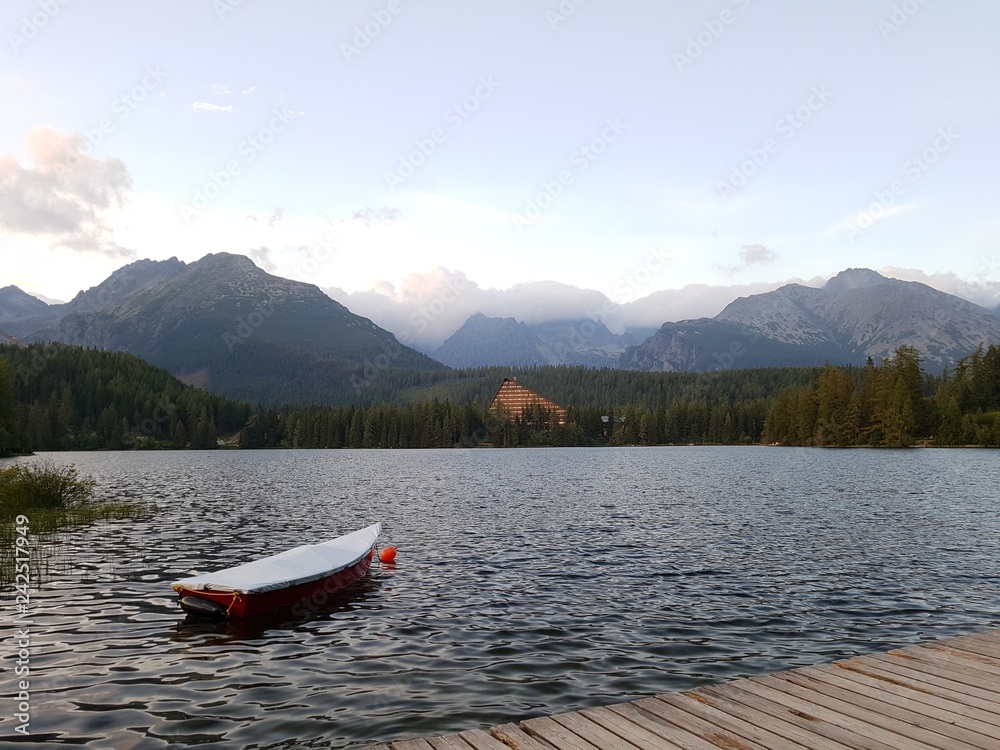 Деревянная лодка на горном озере  на фоне высоких гор 