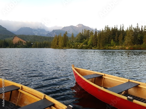 Деревянная лодка на горном озере на фоне высоких гор 