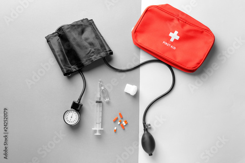 Sphygmomanometer, pills, first aid kit and syringe on grey background. Health care concept