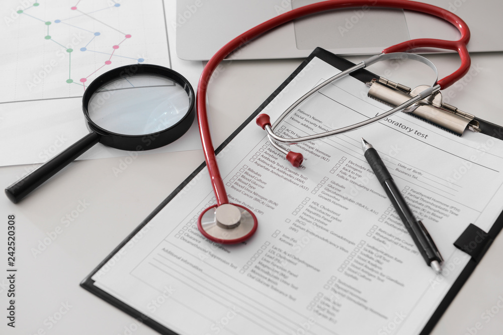 Document with results of laboratory test and stethoscope on table in clinic Document with results of laboratory test and stethoscope on table in clinic