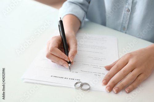 Young woman signing decree of divorce at table, closeup