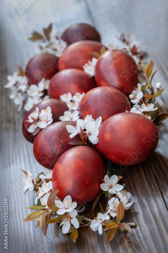 Easter decoration – colored eggs and spring cherry flowers. Close up, selective focus on dark wooden background