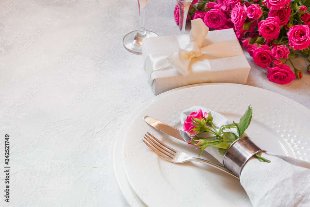Romantic table setting with pink roses, silverware, and decorations. Top view.