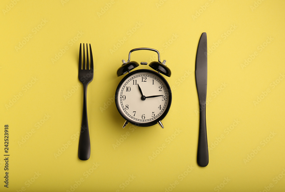 Alarm clock and cutlery on color background. Diet concept - obrazy, fototapety, plakaty 