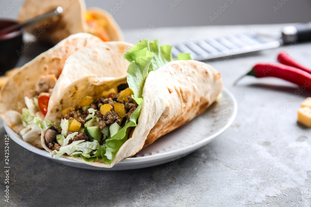 Plate with tasty tacos on grey table