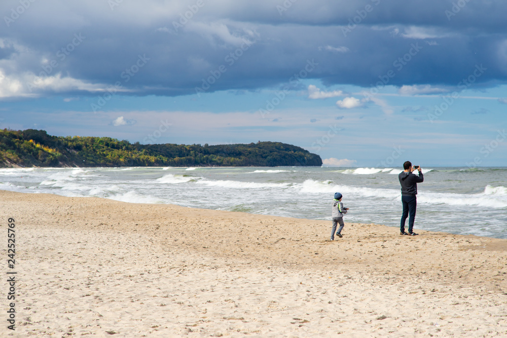 Little boy taking photos with his father at the Baltic Sea beach in Poland