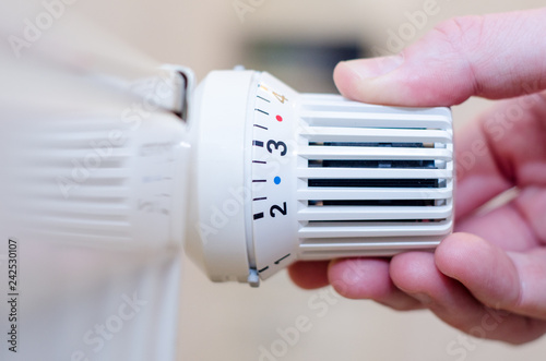 Close Up Of Hand Adjusting Heating Thermostat.