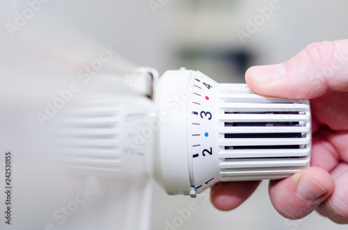 Close Up Of Hand Adjusting Heating Thermostat.