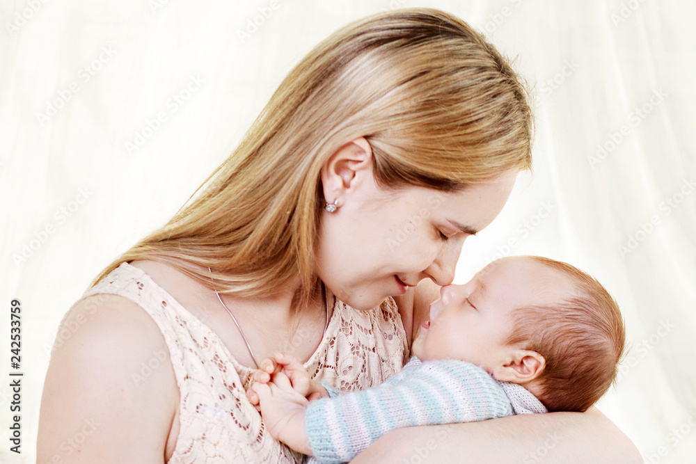Beautiful young mother kissing and hugging her newborn baby boy. Motherhood concept. Happy family concept Beautiful young mother kissing and hugging her newborn baby boy. Motherhood concept. Happy family concept
