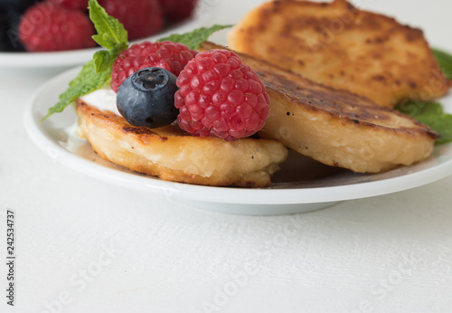 Close-up: Fresh fruit and pancakes are on plate on white wooden table background with copy space for your simple text. Concept: healthy food and tasty breakfast.