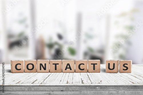 Obraz na płótnie Contact us sign on a wooden desk w salonie