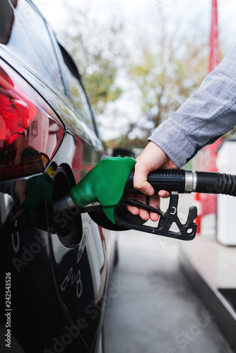 Close up of man refilling tank on his car on the gas station.