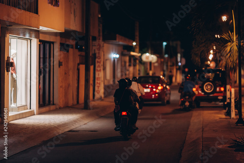 Fototapeta Naklejka Na Ścianę i Meble -  Night street of a small coastal Mexican city. Parked cars, shop windows, bars. Cozumel Island. Mexico
