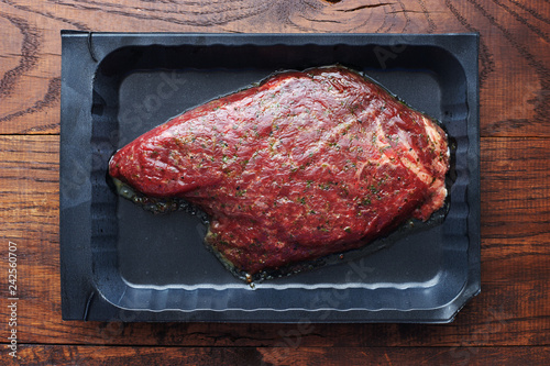 Raw marinated steak with different spices and herbs top view