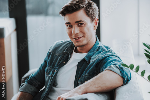 Smiling caucasian man sitting on the sofa and looking