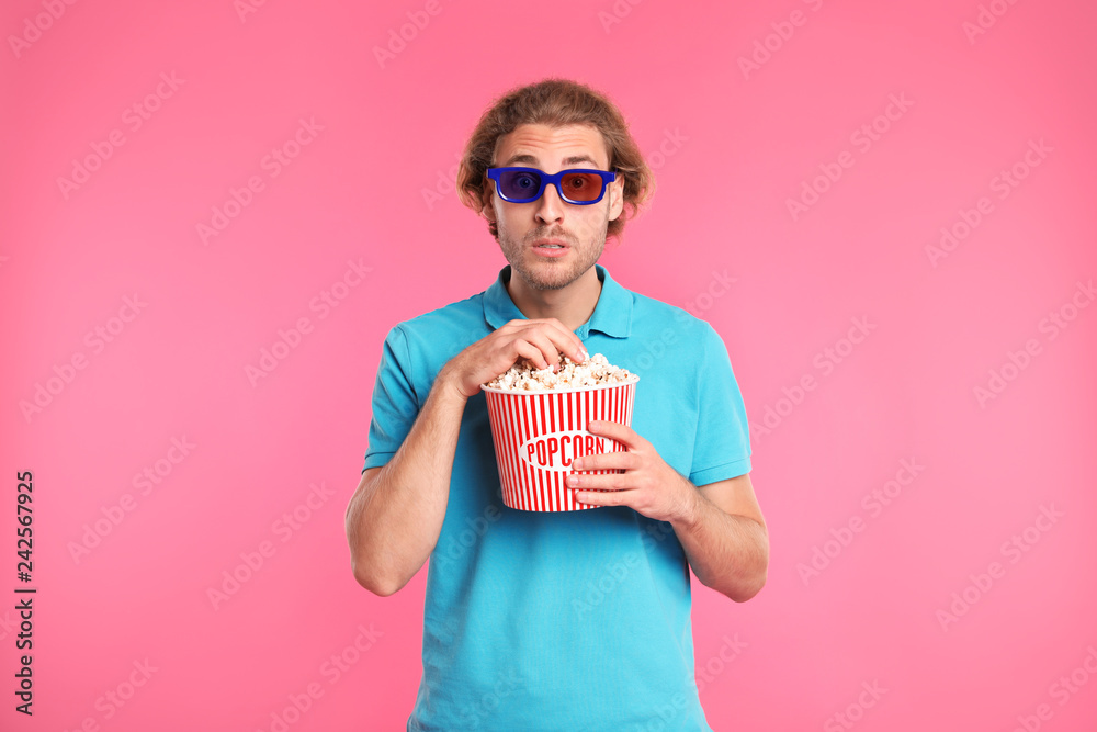 Naklejka premium Emotional man with 3D glasses and popcorn during cinema show on color background
