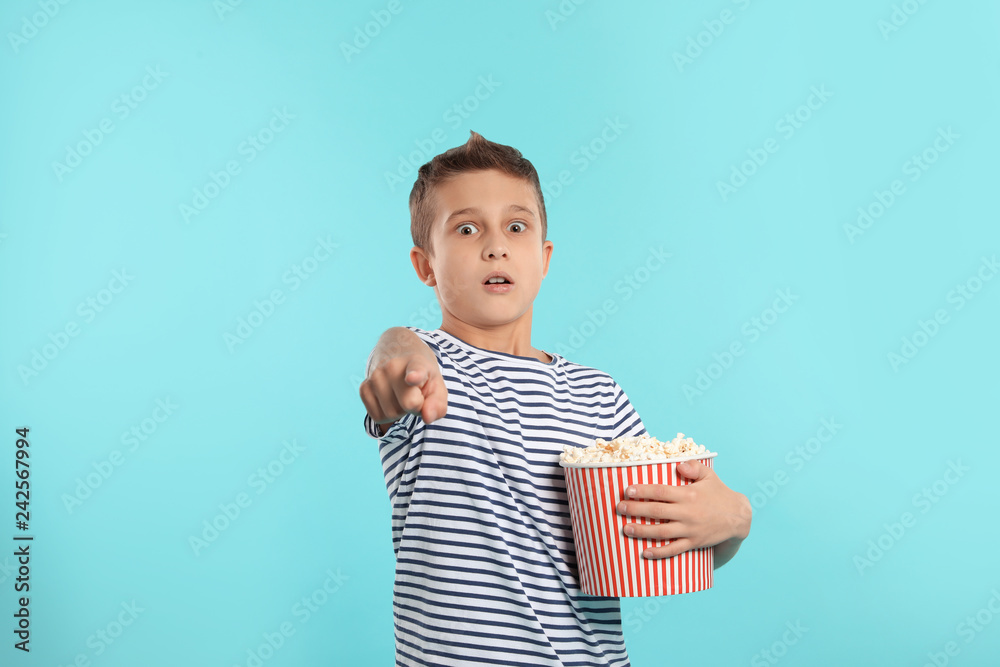 Naklejka premium Emotional boy with popcorn during cinema show on color background