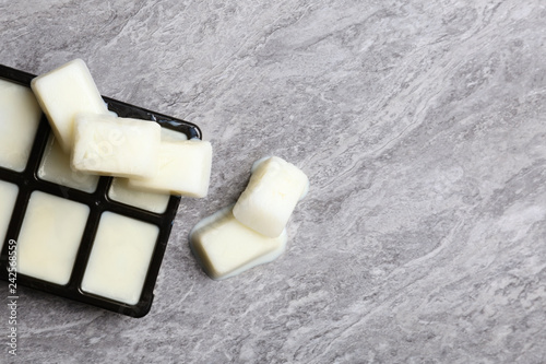 Ice cubes made with milk and tray on grey background, top view. Space for text photo