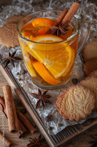 Citrus tea with cinnamon and cardomom in a glass. With sweet homemade almond cookies. Country style. Kraft paper. Wooden background. Close-up. photo