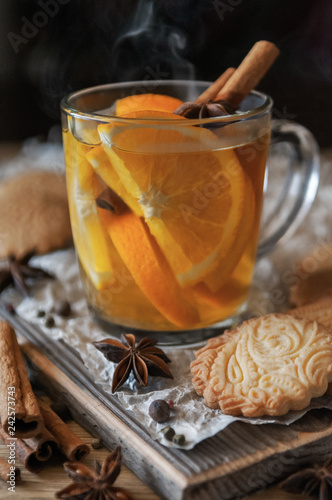 Citrus tea with cinnamon and cardomom in a glass. With sweet homemade almond cookies. Country style. Kraft paper. Wooden background. Close-up. photo