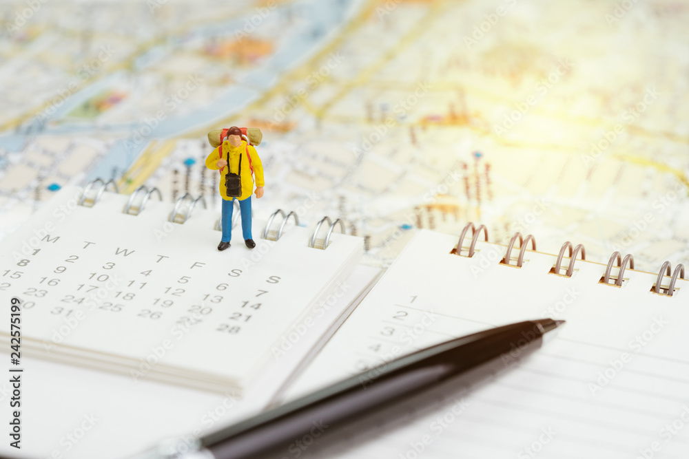 Travel planning or year plan for vacation or start new journey concept, miniature people traveller, backpacker man standing on calendar with pen and city map Travel planning or year plan for vacation or start new journey concept, miniature people traveller, backpacker man standing on calendar with pen and city map