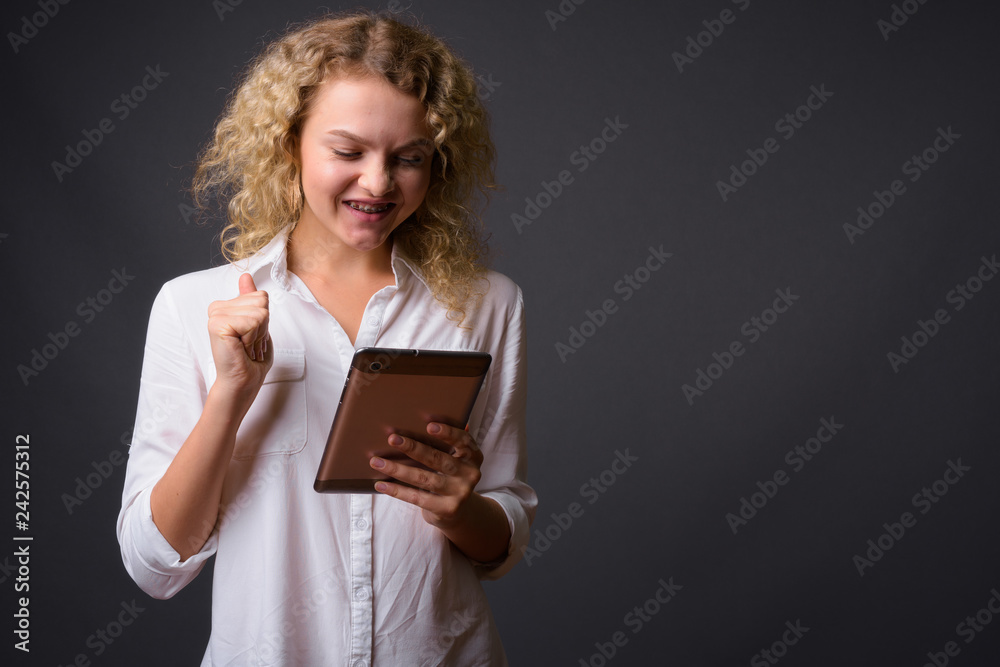 Young beautiful businesswoman with curly blond hair against gray Young beautiful businesswoman with curly blond hair against gray