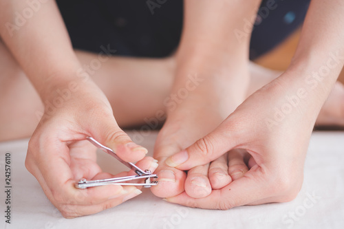 Closeup of a woman cut toenail herself, Foot care treatment and nail, health care concept. photo