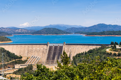 Shasta Dam on a sunny day; the summit of Mt Shasta covered in snow visible in the background; Northern California photo
