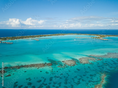 Fototapeta Naklejka Na Ścianę i Meble -  Luxury overwater villas with coconut palm trees, blue lagoon, white sandy beach at Bora Bora island, Tahiti, French Polynesia