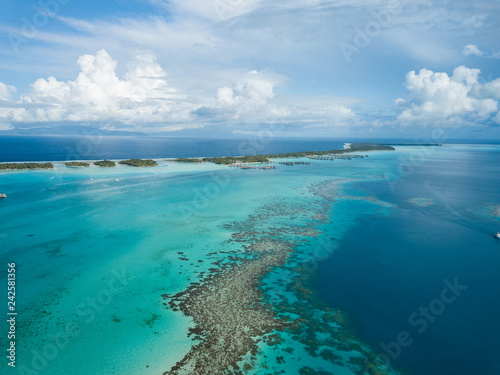 Luxury overwater villas with coconut palm trees  blue lagoon  white sandy beach at Bora Bora island  Tahiti  French Polynesia