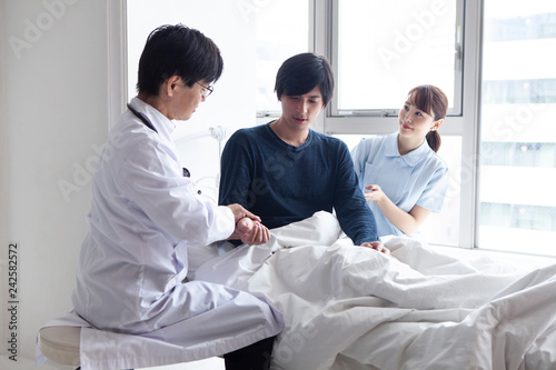入院患者のベッドで様子を確認する医師