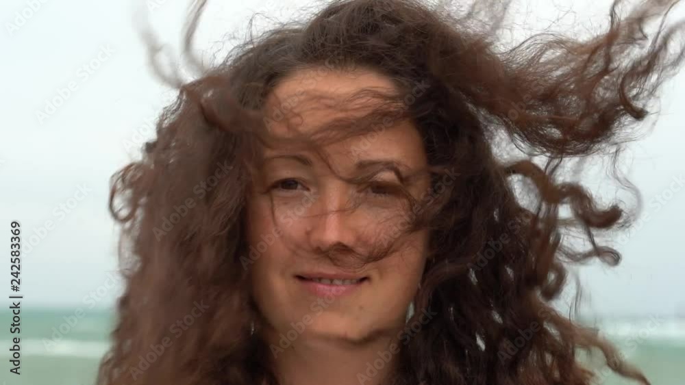 Young woman on the background of the sea waving her head to the side and fluttering hair in the wind. Charming brunette girl on sea coast. Beautiful woman enjoys a wind, the feeling of freedom Young woman on the background of the sea waving her head to the side and fluttering hair in the wind. Charming brunette girl on sea coast. Beautiful woman enjoys a wind, the feeling of freedom