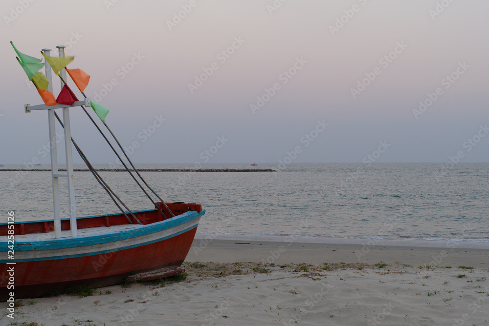 Fototapeta premium Red Fishing Boat with colorful flag parked at one of the beaches in the morning.To be a tsunami warning signal.