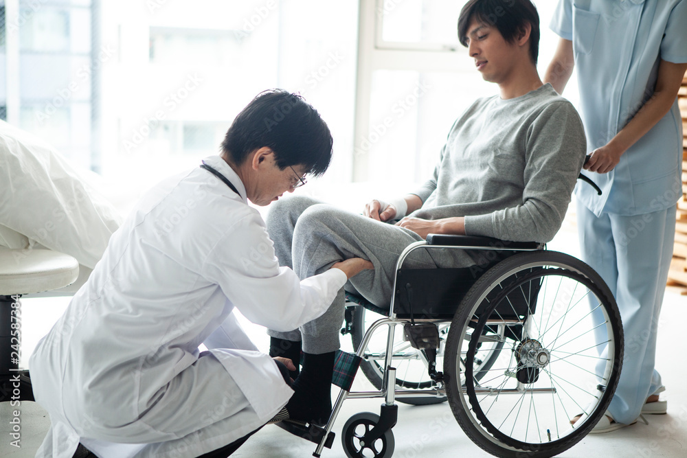 担当医に介助してもらい車椅子に乗る患者