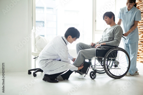 担当医に介助してもらい車椅子に乗る患者