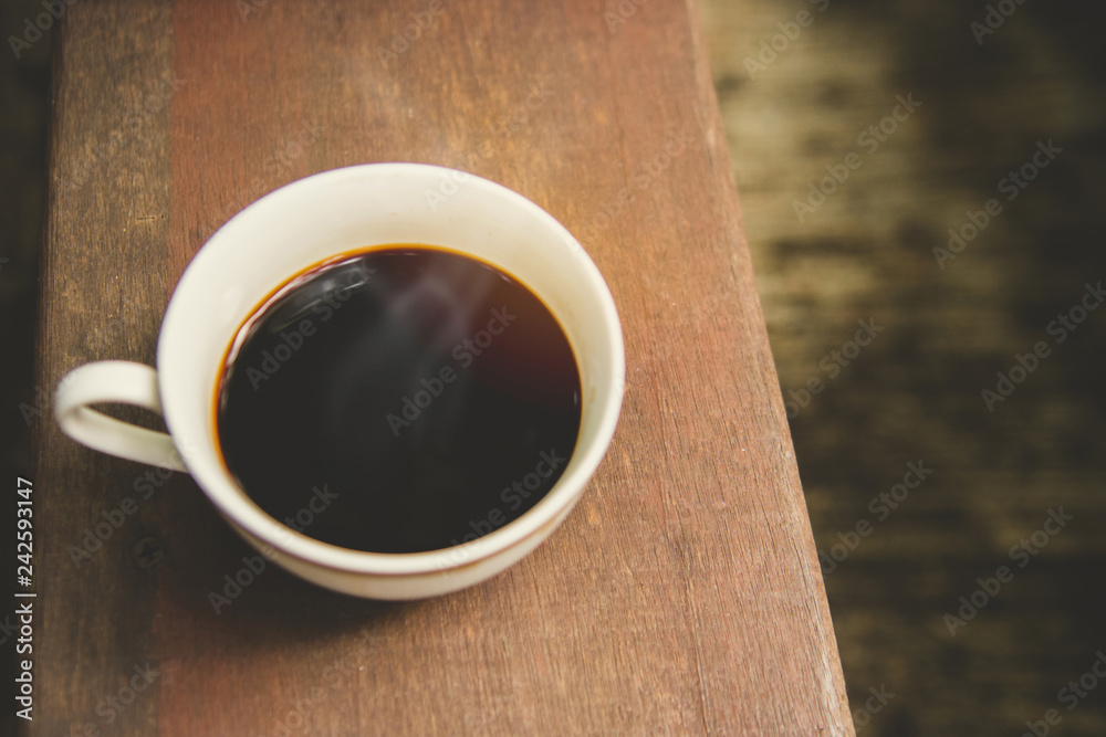 Hot black coffee of white cup with sunshine on dark wooden background.(Top view)