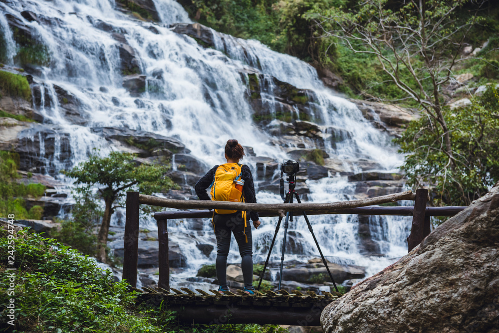 Obraz premium Asian woman travel relax to photograph the waterfalls beautiful. In the winter. at the waterfall mae ya chiangmai in thailand. travel nature. summer