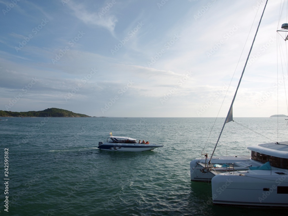 Boat and yacht on the sea. The part of sailing yacht in foreground, speedboat on the surface of water on the center of  the image, islands on the horizon on the background of picture